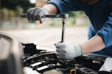 Service outdoor. Close up hands of auto mechanic man working on car engine using wrench to repair...