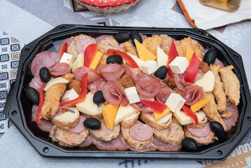 Plate with fried smoked meat, black olives, cheese and red peppers