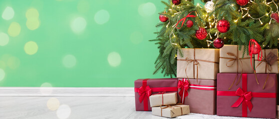 Fototapeta na wymiar Many gifts under Christmas tree near green wall. banner for design