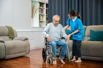 Fototapeta na wymiar Doctor support old man to getting up to exercise, help handicapped elderly stand up, Asian woman nurse helping senior man patient get up from wheelchair for practice walking at home, physical therapy