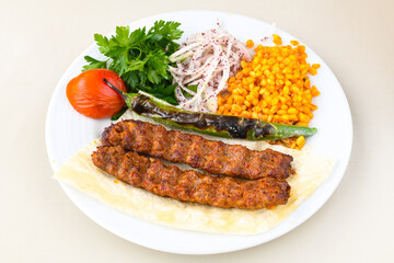 Grilled Turkish Adana, Urfa  Kebab with grilled vegetables, onion and rice on plate. Adana durum.