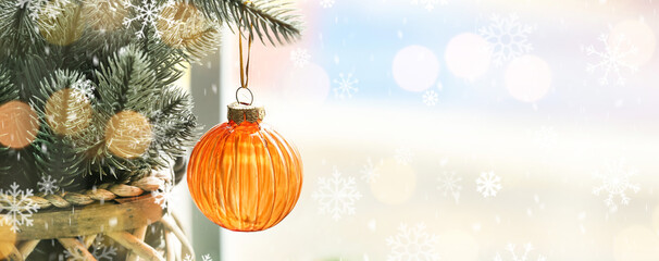 Christmas tree branches with hanging ball near window, closeup