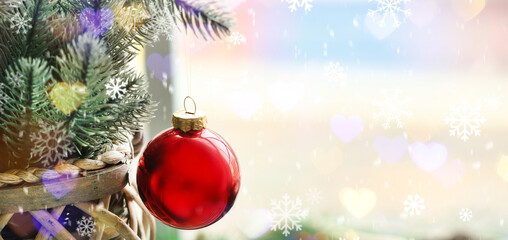 Christmas tree branches with hanging ball near window, closeup