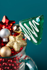Glass with Christmas decorations on dark green background