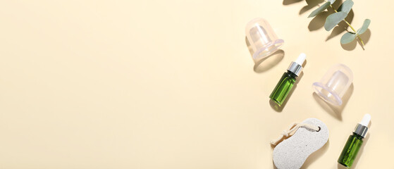 Composition with bottles of essential oil, pumice and vacuum jars for anti-cellulite massage on color background with space for text