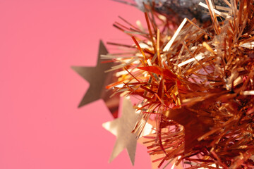 Colorful tinsel Christmas decorations close-up on pink backgorund
