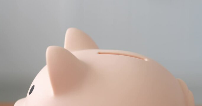 hand put coin into piggy bank for saving money and business investment concept. Macro view