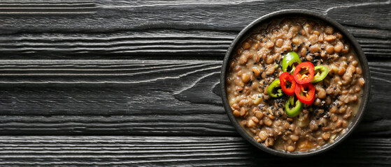 Bowl of tasty lentils soup on black wooden background with space for text