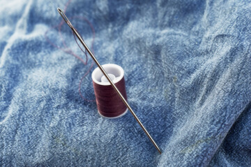 needles and thread on the background of torn jeans the concept of reasonable consumption of needlework for small businesses
