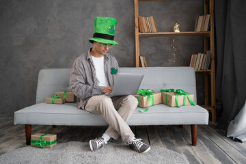 St.Patricks day online shopping. Male buyer with laptop on couch. Guy buys presents, prepare to...