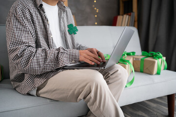 St.Patrick's day shopping online, sales and discounts promotions during spring holidays, online shopping at home. male hands on the laptop with gifts around