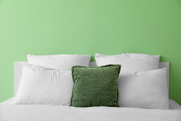 Fototapeta na wymiar Comfortable bed with soft pillows near green wall