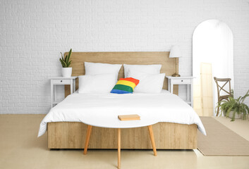 Interior of light bedroom with LGBT pillow and mirror
