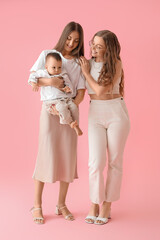 Happy lesbian couple with their little baby on pink background