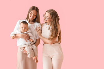 Happy lesbian couple with their little baby on pink background