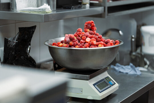 Frozen berry in a bowl on a culinary scales