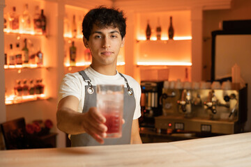 Barman serving red alcoholic cocktail in bar