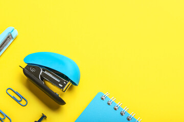 Blue office stapler on yellow background