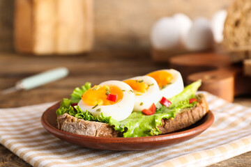 Plate of delicious toast with boiled egg on wooden table, closeup
