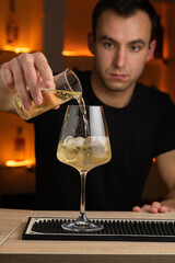 barman gently pours rum into glass. bartender on background.