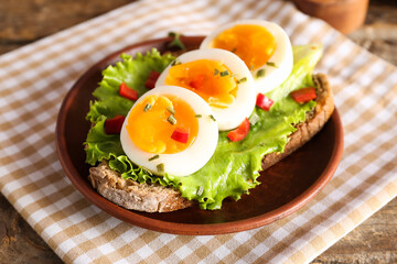 Plate of delicious toast with boiled egg on wooden table, closeup