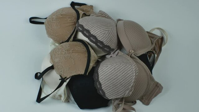 A pile of different classic women's bras on a light background close-up. Underwear beauty, comfort, fashion. Creative beauty concept of women's underwear