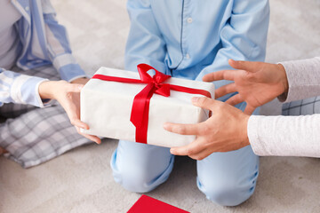 Happy parents with their little son and Christmas present at home, closeup