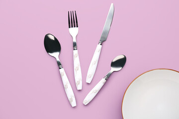 Silver cutlery with plate on lilac background