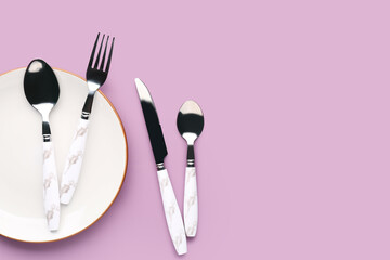 Silver cutlery with plate on lilac background