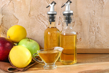 Fruits, gravy boat and bottles of apple cider vinegar on color table