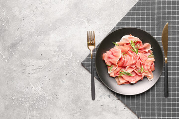 Plate with slices of delicious ham, and cutlery on grunge background