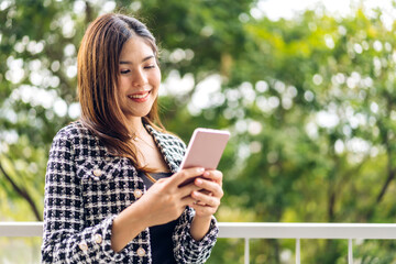 Portrait of smiling happy beautiful asian woman relaxing using digital smartphone.Young asian girl looking at screen typing message and playing game online or social media at cafe