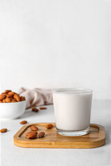Obraz na płótnie Canvas Board with glass of almond milk and nuts on white table