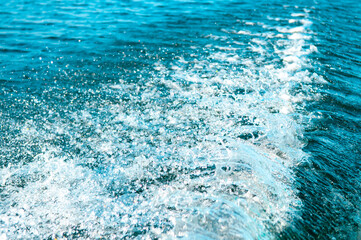 Waves on the sandy beach. Water background, blue sea water. Beautiful texture of sun glare on the water and sea foam.