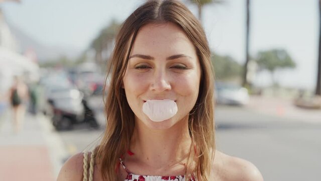 Face, portrait and woman blowing bubblegum in city, street or outdoors. Freedom, comic or funny, carefree and happy female eating gum, laughing and smiling downtown, having fun or being playful alone