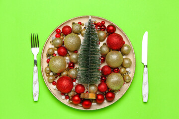 Table setting with Christmas tree and balls on green background