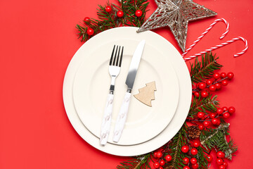 Table setting with Christmas branches, cranberry and candy canes on red background