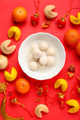 Bowl of tasty tangyuan, fortune cookies, mandarins and Chinese decor on red background. Dongzhi...