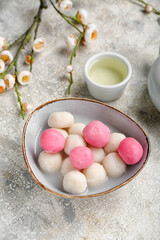 Bowl of tangyuan, cup and sakura on grunge background. Dongzhi Festival