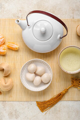 Mat with bowl of tangyuan, fortune cookies, mandarins, cup and teapot on grunge background. Dongzhi Festival