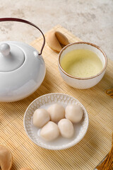 Mat with bowl of tangyuan, cup and teapot on grunge background. Dongzhi Festival