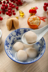 Spoon and bowl of tangyuan on wooden background, closeup. Dongzhi Festival
