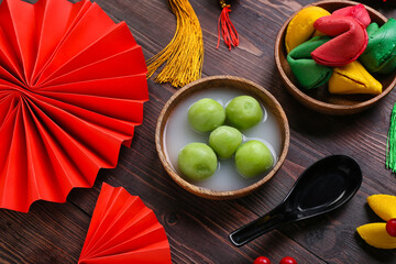 Bowl of tangyuan, fortune cookies and Chinese decor on dark wooden background. Dongzhi Festival