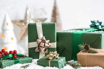 Fototapeta na wymiar Christmas gift boxes with fir branches on white snow, closeup