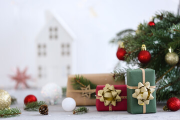 Christmas gift boxes with fir branches and balls on white table, closeup