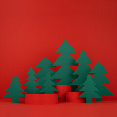 Festive Christmas background with three red cylinder podiums mockup, green paper spruces for presentation cosmetic product, gifts, goods, copy space, square. New Year template for advertising.