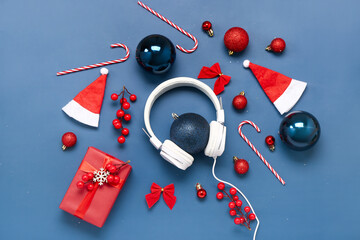 Headphones with Christmas decor, Santa hats and gift on blue background