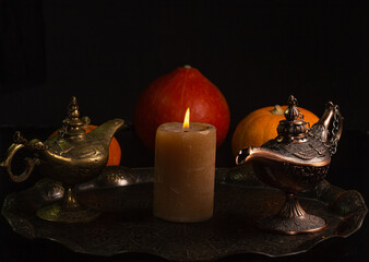 Yellow-orange pumpkins candle tray Aladdins lamp on a black background the concept of Halloween and the autumn harvest of pumpkin close-up copyspace from above