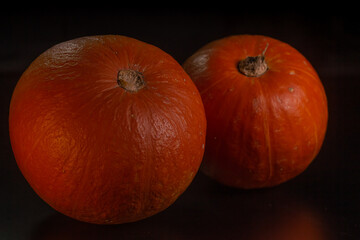 Yellow-orange pumpkins on a black background the concept of Halloween and the autumn harvest of pumpkin close-up copyspace from above