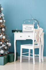 Vase with tree branches, Christmas balls, laptop and gift on table in office